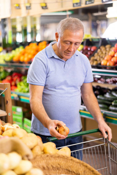 un vieil homme acheteur achetant des oignons à l’épicerie - market stall spain fruit trading photos et images de collection