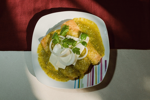 Mexican enchiladas verdes, a staple food in Mexican cuisine, are served on a plate