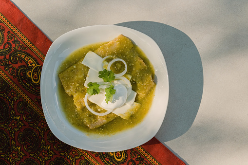 Mexican enchiladas verdes, a staple food in Mexican cuisine, are served on a plate