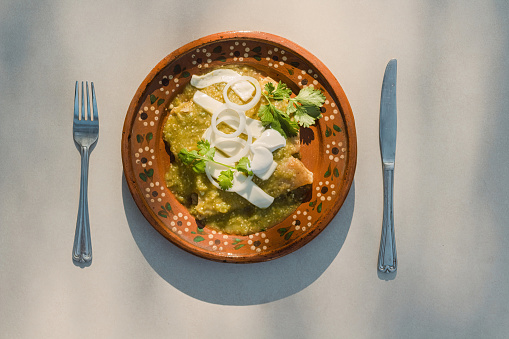 Savor the authentic Mexican flavor of green enchiladas served on a plate with silverware