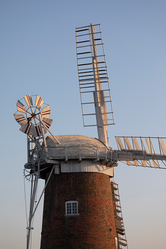 A white smock mill built in 1869 onto a two storey red brick base with attached miller’s cottage,