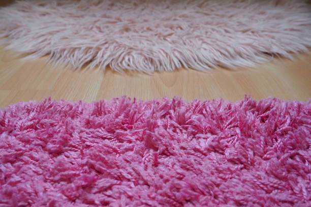 Long pile rug in pink on a beige laminate floor. Feminine interior for a room or bedroom of a girl or woman. Interior design in pink tones. Flooring is laminate. The role of dust mites in allergies. stock photo