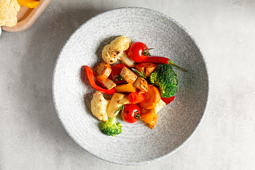 Roasted vegetables. Baked vegetables in plate on concrete background. Top view,