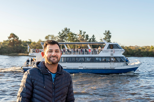 Latin man posing in front of a boat on the river