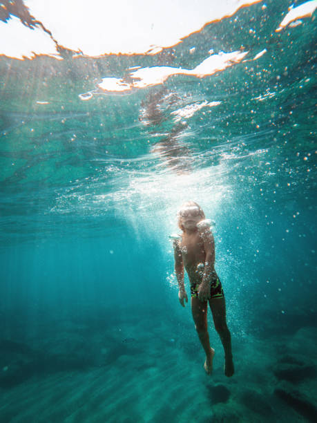 istock Little Blonde Kid Moving Up Underwater 1500450043
