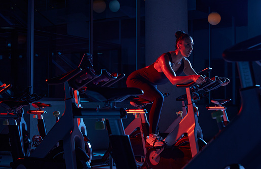 Athlete woman training on stationary bike in fitness gym.