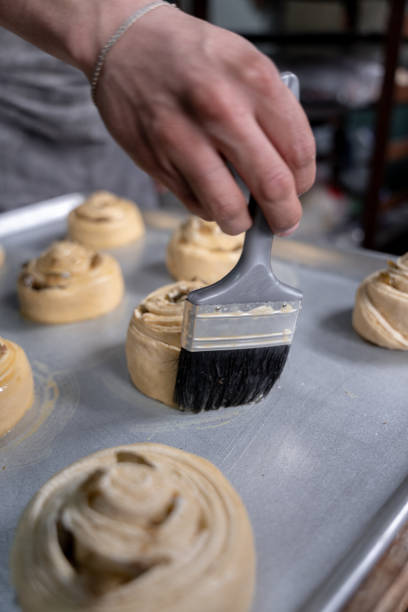 istock A young Hispanic baker is using a brush to egg glaze some cinnamon rolls 1500461782