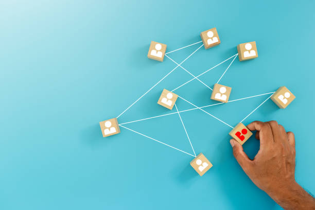 istock Networking concept. Man holding wooden human icons connection communication network blue background. teamwork link management corporate. blue banner copy space. 1500464356