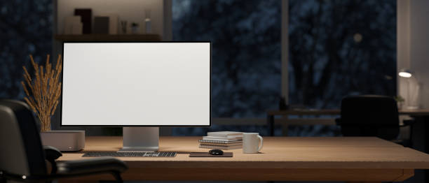 istock A computer mockup and decor on a wooden table in a modern dark office room at night. 1500465814