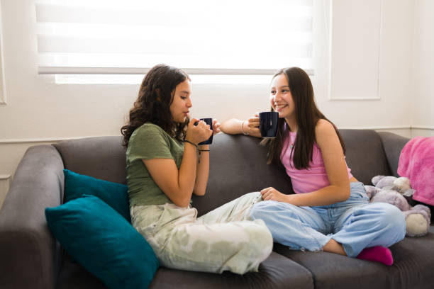 istock Beautiful teenagers drinking tea and talking on the sofa 1500468974