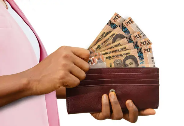 Photo of fair Hand Holding brown Purse With Sierra Leonean Leone notes, hand removing money out of purse isolated on white background