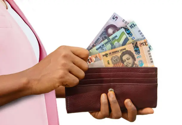 Photo of air Hand Holding brown Purse With Sierra Leonean Leone notes, hand removing money out of purse isolated on white background