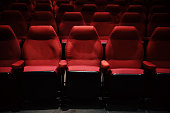 Interiors of empty comfortable red cinema chairs. Low-key. Dark tone.