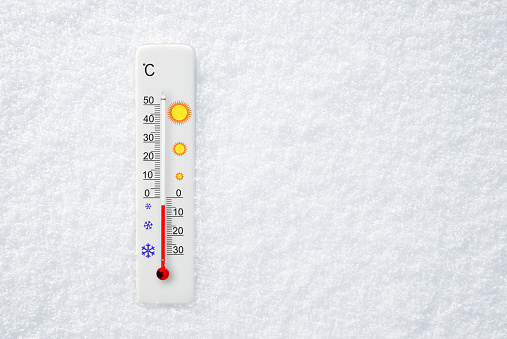White celsius scale thermometer in snow. Ambient temperature minus 4 degrees celsius