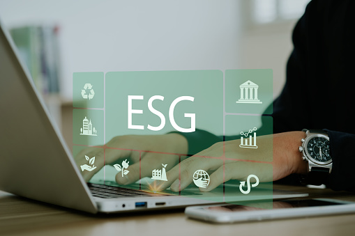 Businessmen use a computer to analyze ESG, surrounded by ESG icons close to the computer screen in business investment strategy concept.