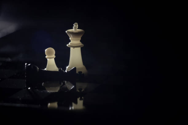 istock chess pieces on a chessboard in a dark room illuminated by a lamp 1500484702