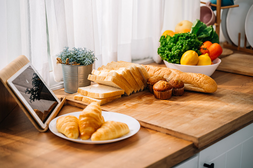 Fresh homemade baked bread and sliced bread and vegetables and fruits on wooden table in living room, Food for breakfast or lunch, Healthy vegetarian food concept, Healthy lifestyle
