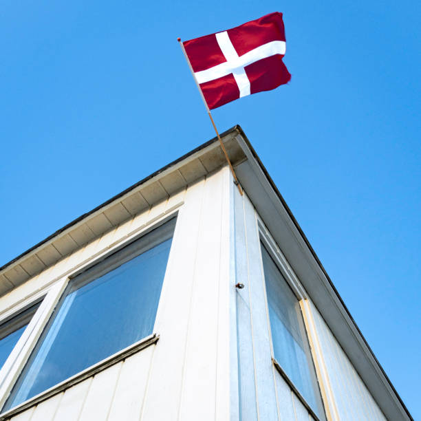 mirando hacia una casa de baños en la playa de løkken, una bandera danesa ondeando - løkken fotografías e imágenes de stock