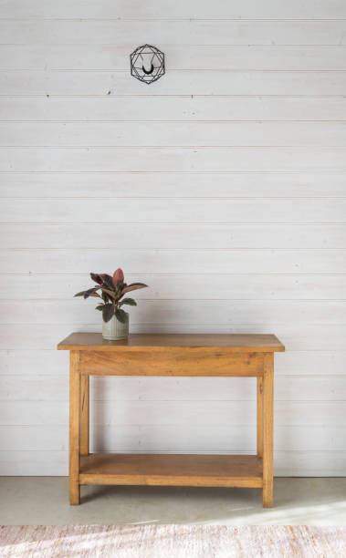 Vertical view of colourful leafy plant in grey pot on oak side table