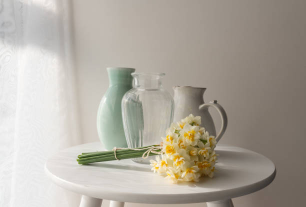 istock Close up of jonquils laying on table with three vases 1500490296