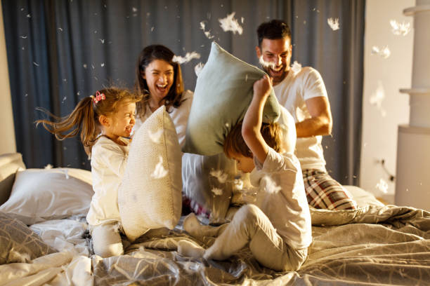 familia feliz teniendo una pelea de almohadas en el dormitorio. - bed couple pillow fight men fotografías e imágenes de stock