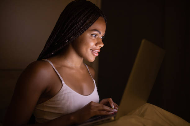 istock Pretty black woman using laptop on bed. Woman using laptop at night. 1500492903