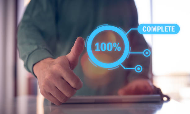 istock Man give a thumb up stamp on screen of project complete 100 percent 1500494033