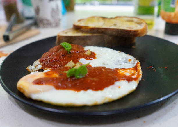 istock Breakfast plate with fried eggs and tomato sauce garnished with herbs 1500494296