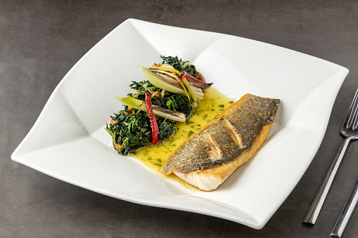 Grilled sea bass fillet served with garnishes in a fine dining restaurant