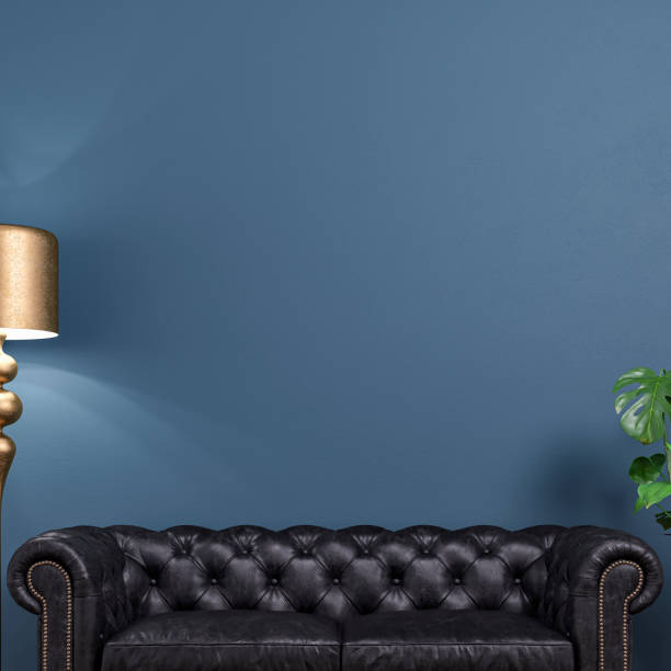 Cozy retro-chic interior with a black leather cushion sofa, a retro golden electric lamp, and a potted plant (monstera) in front of an Aegean blue wall background with a large picture frame with passe-par-tout and copy space. A waiting room like a doctor's or lawyer's office. A slight vintage effect was added. 3D rendered image.