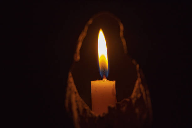 istock lighted candle stands in a dark room close-up 1500496438