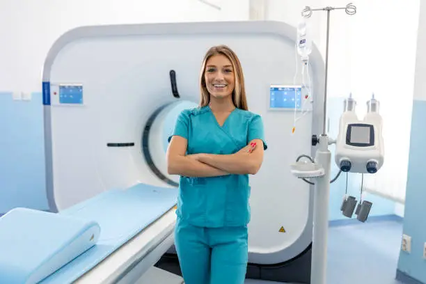 Photo of Beautiful happy female doctor physician radiologist standing in CT CAT Scan room at hospital.