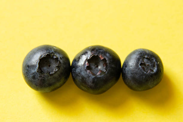 ripe blueberries on a yellow background close-up ripe blueberries on a yellow background close up dissert stock pictures, royalty-free photos & images