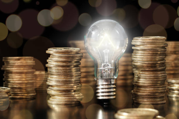 Financial literacy image. Knowledge of managing money. Lightbulb and stack of coins. right managed stock pictures, royalty-free photos & images