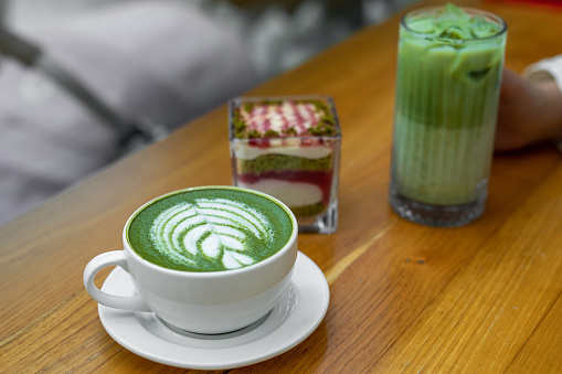 Matcha latte green milk foam cup on wood table at cafe