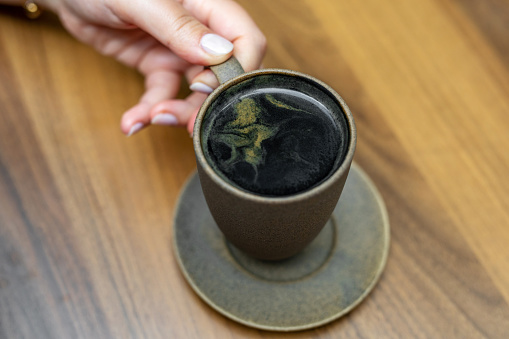 Woman holding a cup of Goth Latte or Charcoal Latte