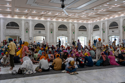 New Delhi, India - April 11, 2023: People eating in the food hall of Gurudwara Bangla Sahib, a famous Sikh house of worship.
