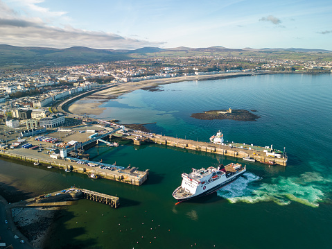 Douglas, Isle of Man - 25 march 2023: Passenger ferry maneuvering when docking in the Douglas harbor and Central Promenade visible in the background