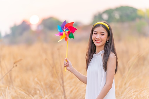 Woman hand holding a colored big pinwheel on a cypress background with copy space