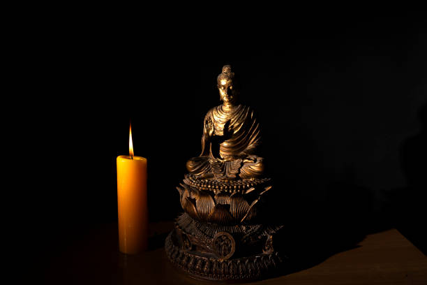 istock Buddha statue with a burning candle on black background 1500510837