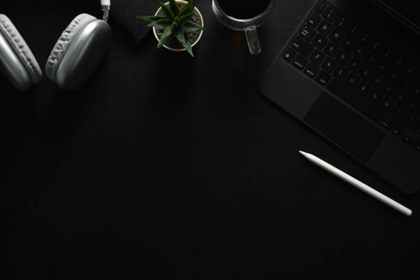 istock Dark modern workplace with laptop, coffee cup and wireless headphone on black leather. Top view with copy space. 1500513298