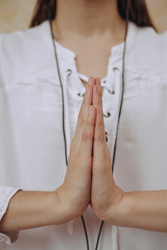 Crop female with Namaste hands doing yoga and meditating in prayer pose while leading healthy lifestyle