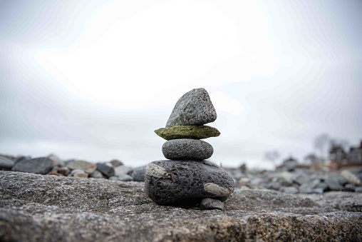 Green and gray stones in a beautiful balanced stack ona rocky Massachusetts New England  shoreline, focus meditation background concepts