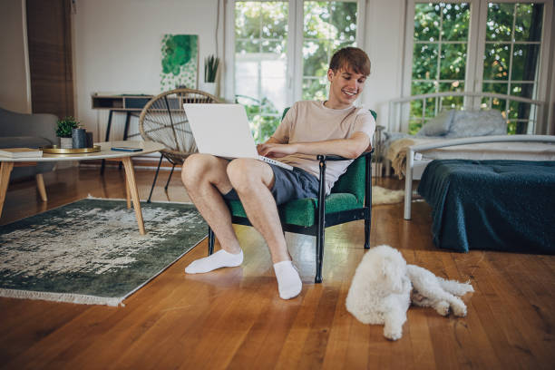 istock Young man using laptop at home and spending time with his dog 1500519154