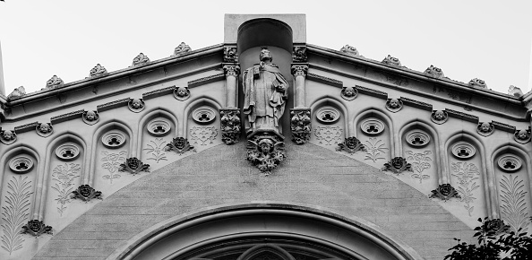 Shot in black and white detail on the facade of this historic building representing some character, animal or flower.