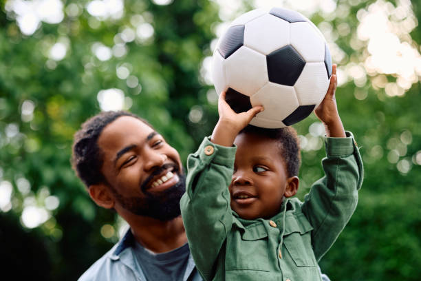 istock Happy black boy holding a ball while playing with his father outdoors. 1500523986