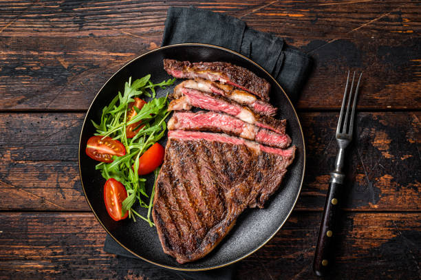 和牛リブアイ牛肉ステーキを皿にのせて焼いてスライスしたバーベキュー。暗い背景。平面図 - rib eye steak beef cutting board meat ストックフォトと画像