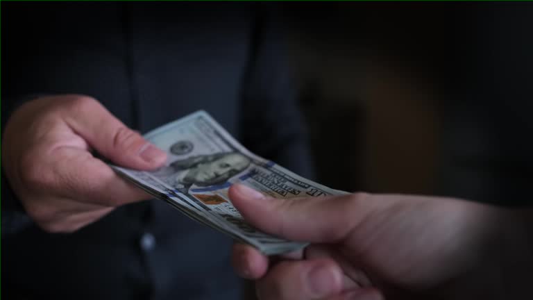 Man in classic black shirt gives pack of banknotes and returns it back