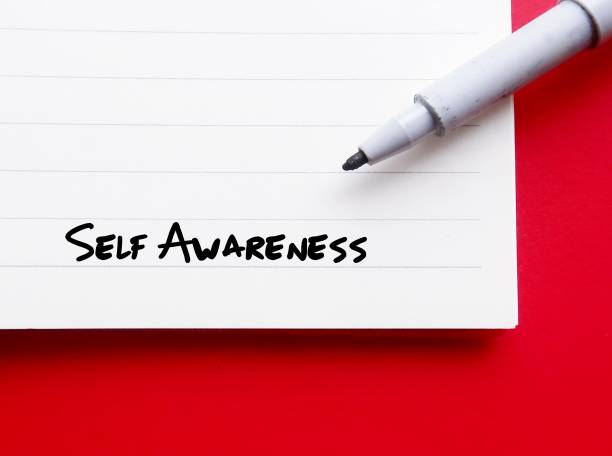 On red background, pen wrote on notebook SELF AWARENESS, individual consciously knows themselves, understands character, trait and feeling knowing their own values, beliefs personal preferences