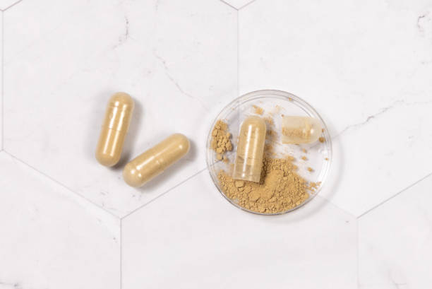 istock Taking dietary supplements with capsules. One capsule Opened in a jar on marble table 1500529536